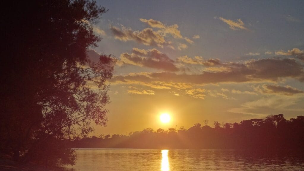 Voo para o Cristalino Jungle Lodge: como chegar a Alta Floresta de avião fretado 6 Pôr do sol refletido em rio de Alta Floresta, no norte de Mato Grosso, com silhueta da floresta amazônica