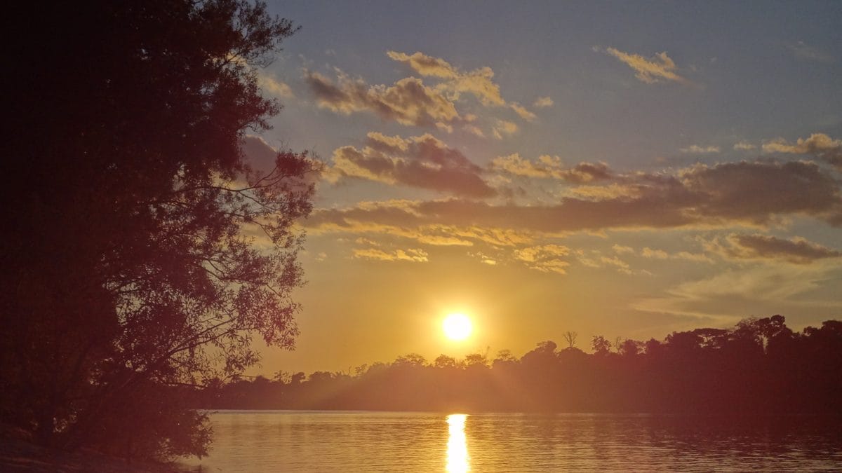 Pôr do sol refletido em rio de Alta Floresta, no norte de Mato Grosso, com silhueta da floresta amazônica