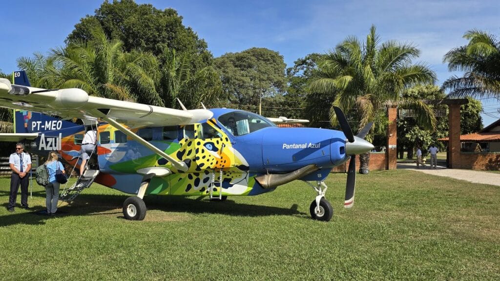 Voo para o Refúgio Ecológico Caiman: 50 minutos de Campo Grande à pista da fazenda 7 Cessna Grand Caravan da VoeMTX em pista de grama de fazenda no Pantanal, com palmeiras ao fundo